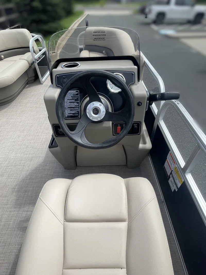 Slide: The Image of 2025 Sun Tracker Party Barge 16 DLX steering console with beige seating. - 4
