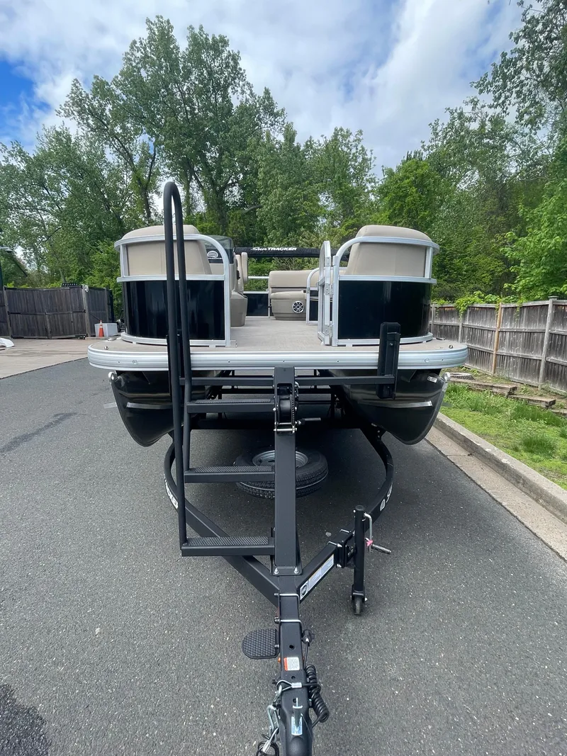 Slide: The Image of 2025 Sun Tracker Party Barge 16 DLX pontoon boat on trailer, parked on a road. - 6