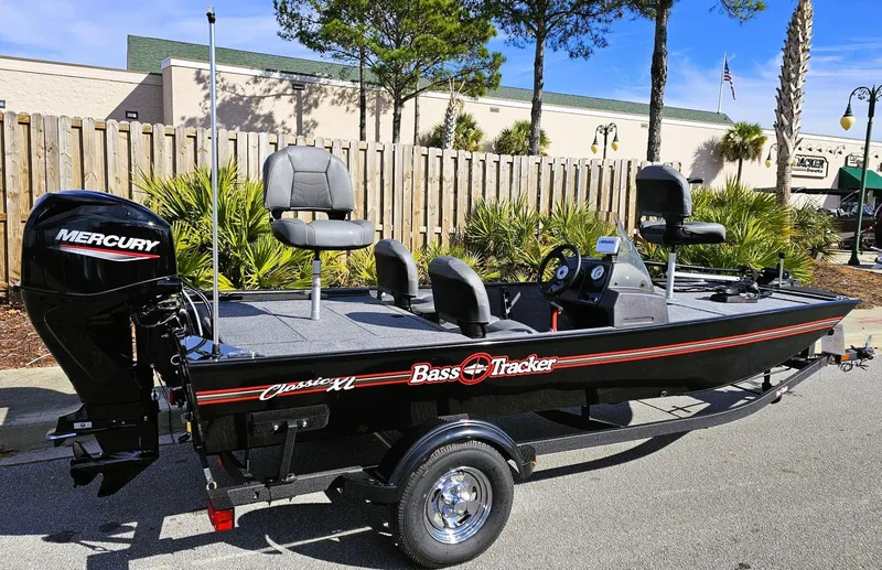 Slide: The Image of 2025 Tracker Bass Tracker Classic XL boat with Mercury engine, parked outdoors. - 2