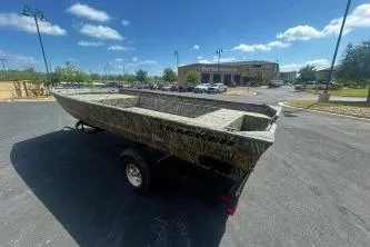 Slide: The Image of 2025 Tracker Grizzly 2072 Utility boat on trailer in parking lot under blue sky. - 2