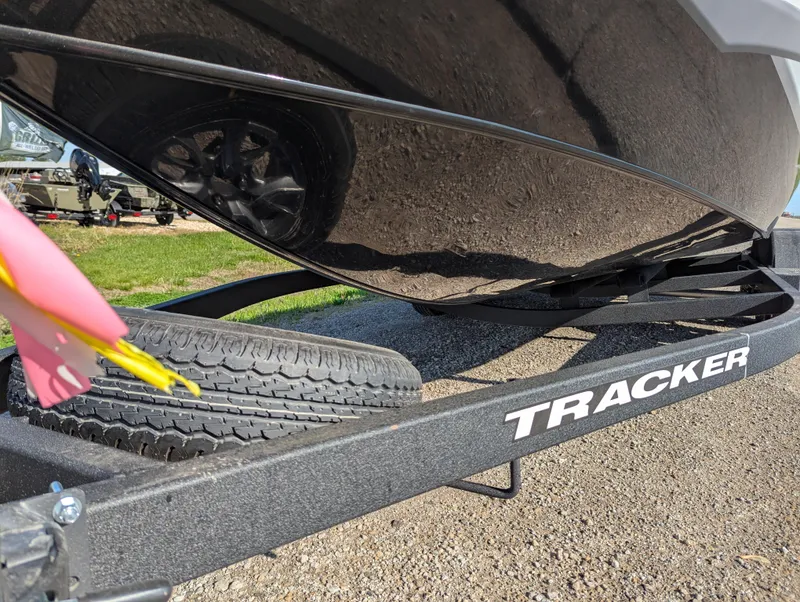 Slide: The Image of 2025 Tracker Savage 215 boat trailer with tire, parked on gravel. - 12