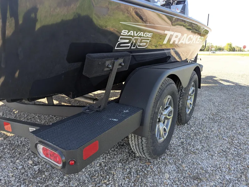 Slide: The Image of 2025 Tracker Savage 215 boat on a dual-axle trailer, parked on gravel. - 7