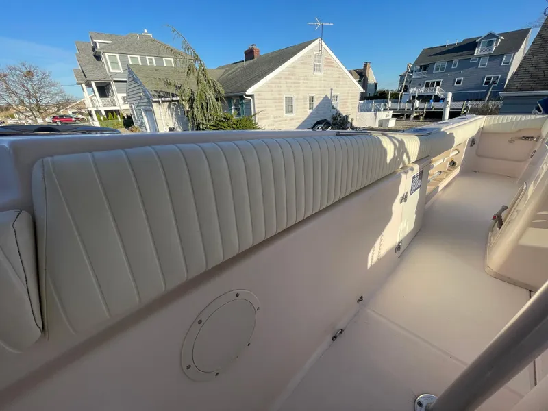 Slide: The Image of 2008 Grady-White Bimini 306 boat interior with white cushioned seating, docked near coastal homes. - 28