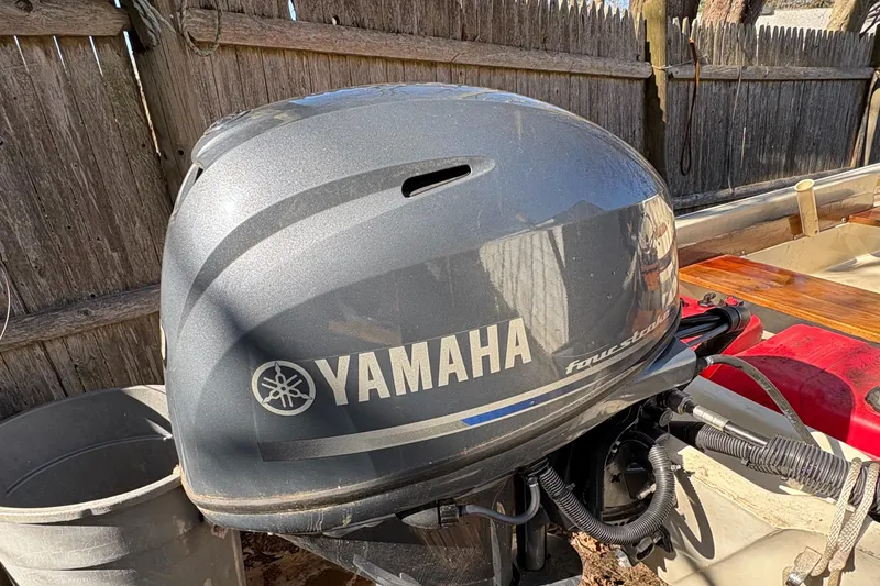 Slide: The Image of Yamaha outboard motor on a 1987 Boston Whaler 13, parked near a wooden fence. - 10