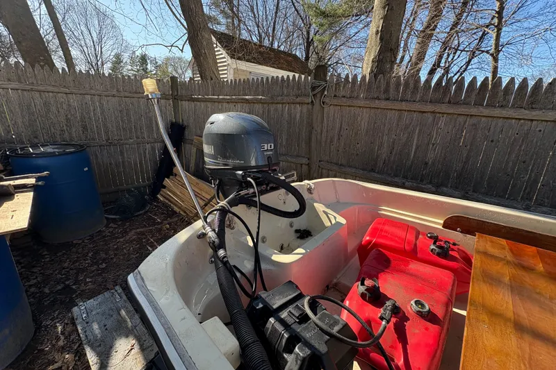 Slide: The Image of 1987 Boston Whaler 13 boat with Yamaha 30 outboard motor in a fenced yard. - 11