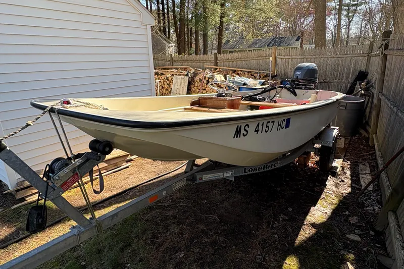 Slide: The Image of 1987 Boston Whaler 13 boat on trailer, parked beside a house, with outboard motor. - 5