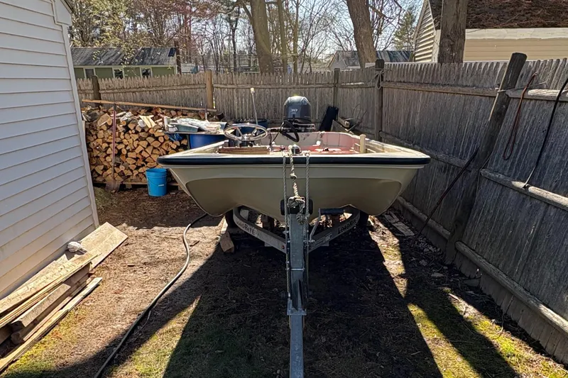 Slide: The Image of 1987 Boston Whaler 13 boat on trailer, parked in a backyard near woodpile. - 6