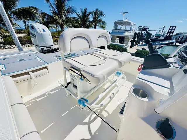 Slide: The Image of 2021 Sea Born FX24 boat interior with seating and console, docked near palm trees. - 11