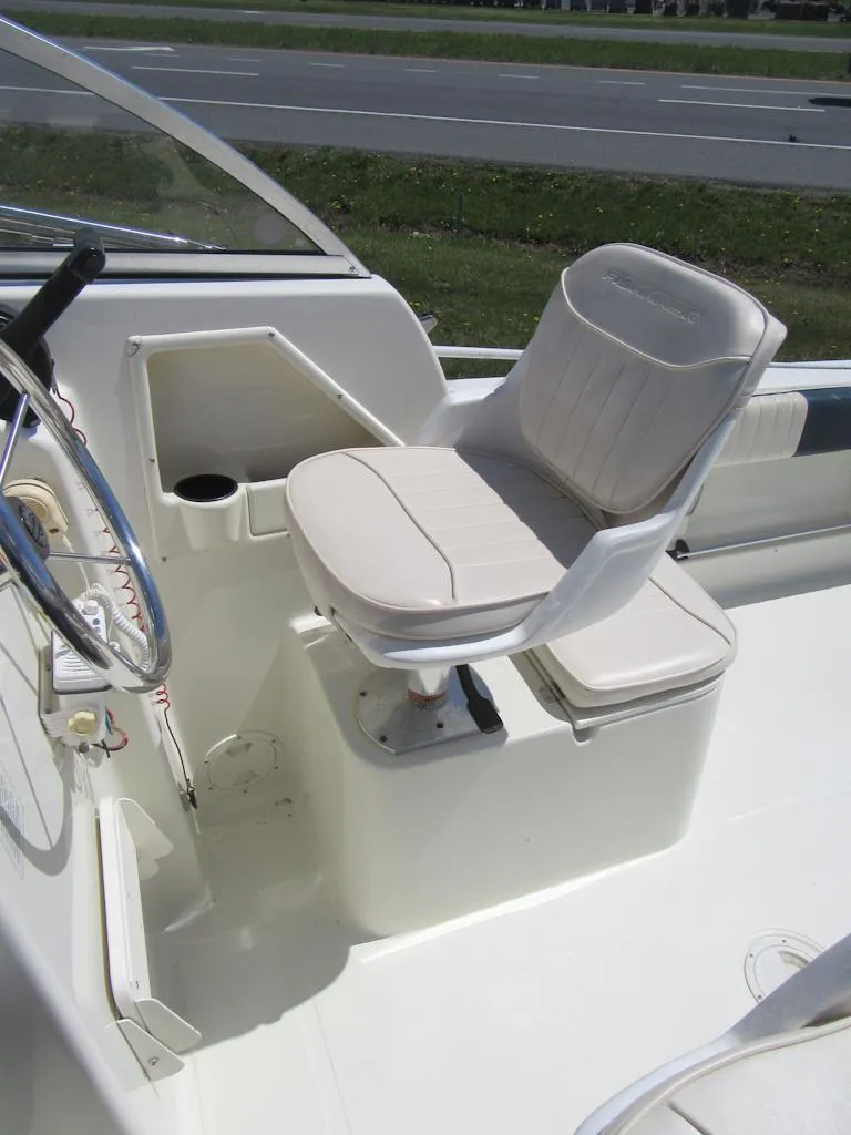 Slide: The Image of Captain's seat on 2002 Fish Hawk 210 WA boat, featuring white upholstery and steering wheel. - 11