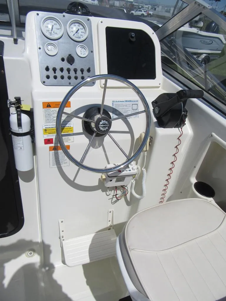 Slide: The Image of Control panel of a 2002 Fish Hawk 210 WA boat with steering wheel and gauges. - 12