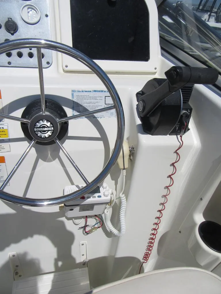 Slide: The Image of Steering wheel and controls of a 2002 Fish Hawk 210 WA boat. - 14