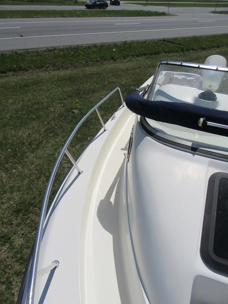 Slide: The Image of 2002 Fish Hawk 210 WA boat, side view, parked on grass near a road. - 21