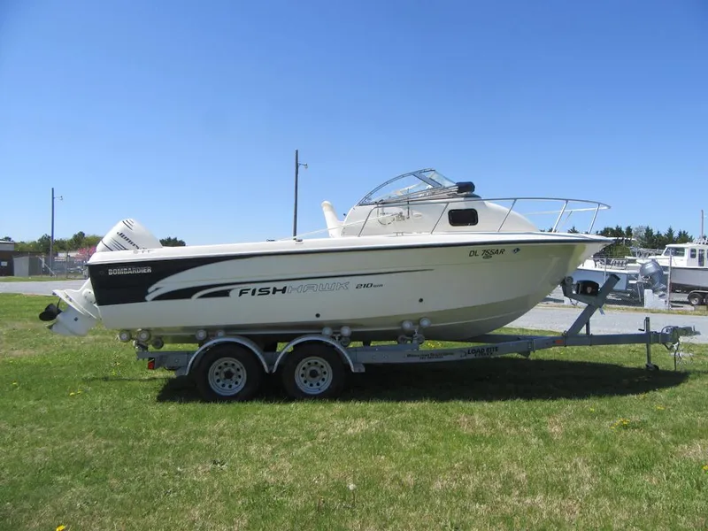 Slide: The Image of 2002 Fish Hawk 210 WA boat on trailer, parked on grass under clear sky. - 3