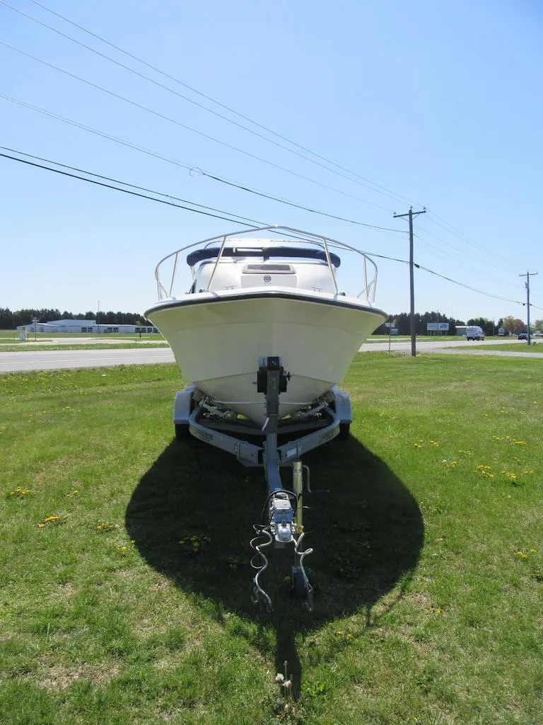 Slide: The Image of 2002 Fish Hawk 210 WA boat on trailer, parked on grass under clear sky. - 4