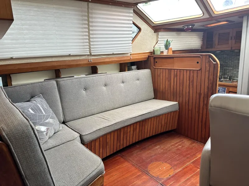 Slide: The Image of Cozy interior of 1986 Slocum 43 sailboat with wooden paneling and gray seating. - 10