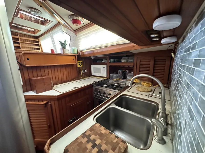 Slide: The Image of 1986 Slocum 43 yacht kitchen with wooden cabinetry, dual sink, and modern appliances. - 14