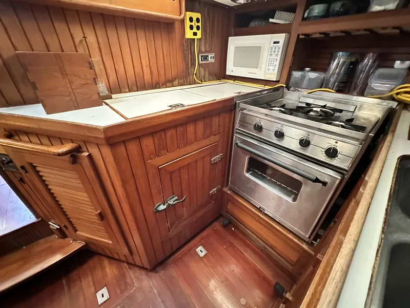 Slide: The Image of 1986 Slocum 43 yacht kitchen with wooden cabinetry, stove, and microwave. - 15