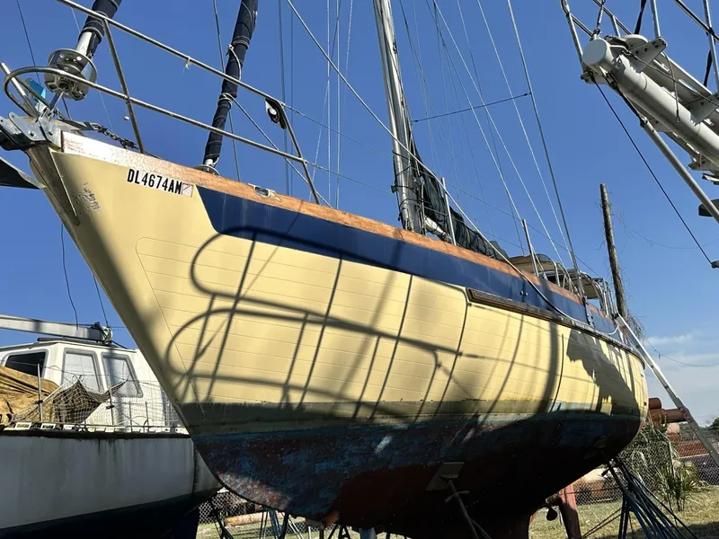 Slide: The Image of 1986 Slocum 43 sailboat on land, blue sky background, hull in shadow. - 2