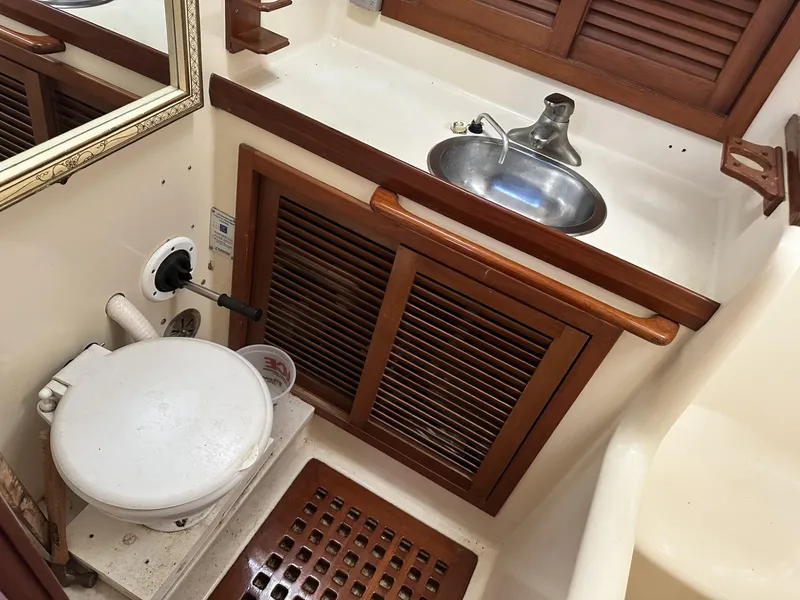 Slide: The Image of 1986 Slocum 43 yacht bathroom with sink, toilet, and wooden cabinetry. - 24
