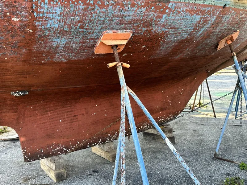 Slide: The Image of A 1986 Slocum 43 sailboat hull on stands, showing weathered paint and marine growth. - 35