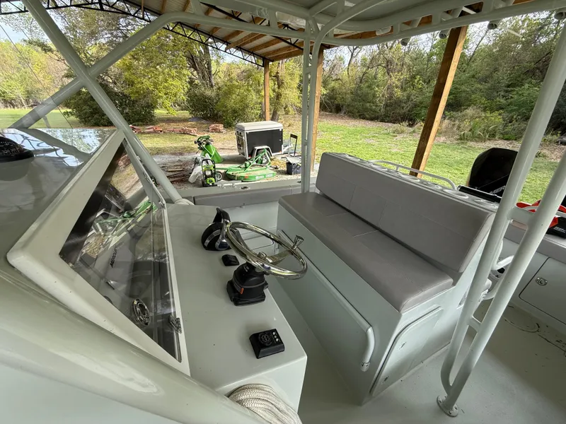 Slide: The Image of 2004 Boston Whaler Guardian 27 interior with steering wheel and seating, under a canopy. - 14