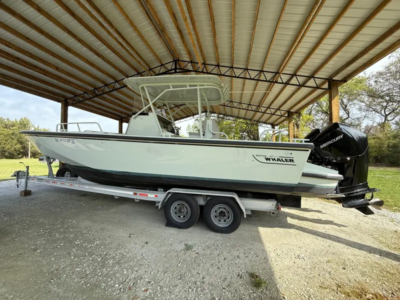 Slide: The Image of 2004 Boston Whaler Guardian 27 boat on trailer under a metal canopy. - 2