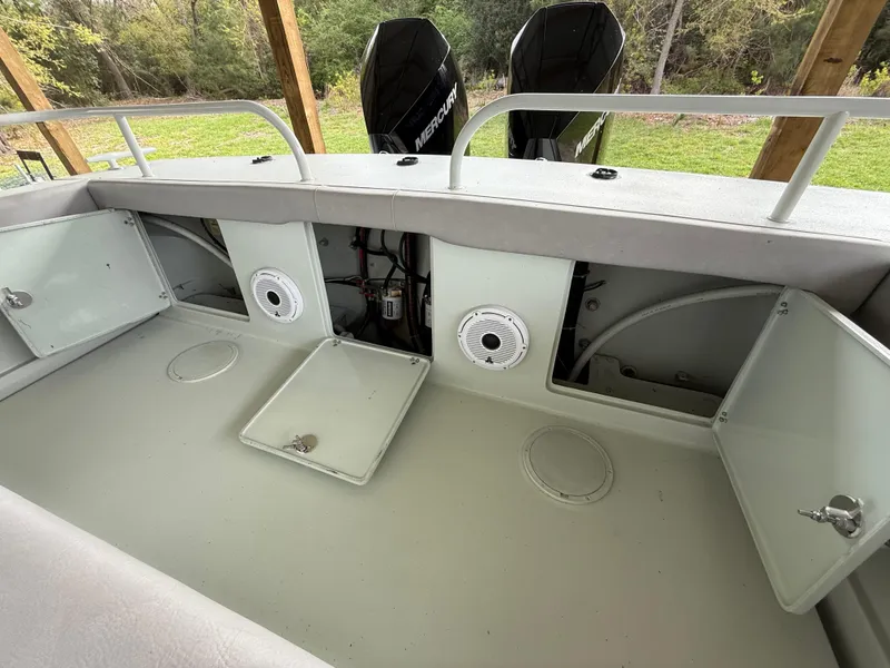 Slide: The Image of 2004 Boston Whaler Guardian 27 boat interior with open storage compartments and dual Mercury engines. - 22