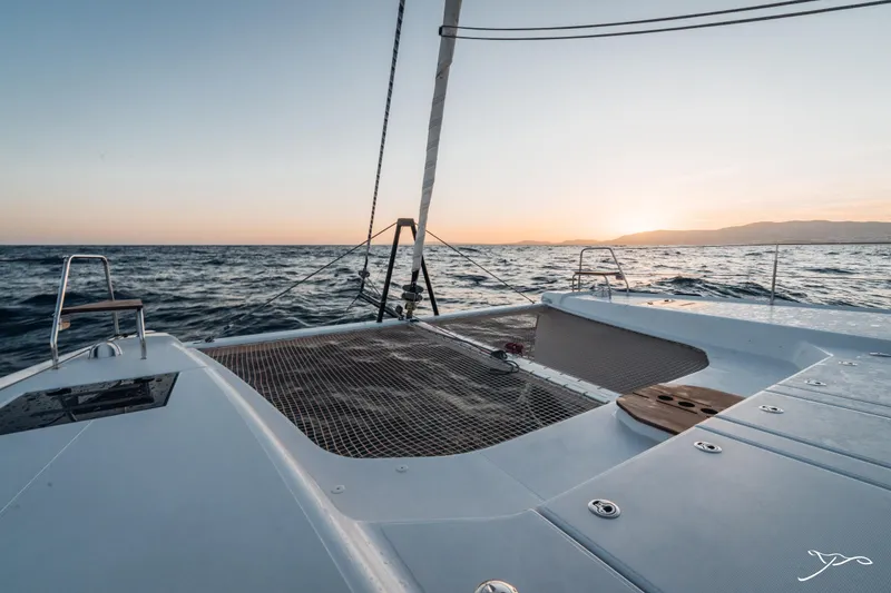 Slide: The Image of 2025 Nautitech 44 Open catamaran at sea during sunset, showcasing deck and netting. - 11