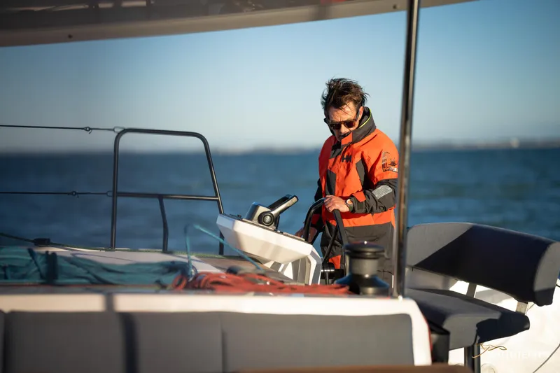 Slide: The Image of Man steering 2025 Nautitech 48 Open catamaran on open water. - 15
