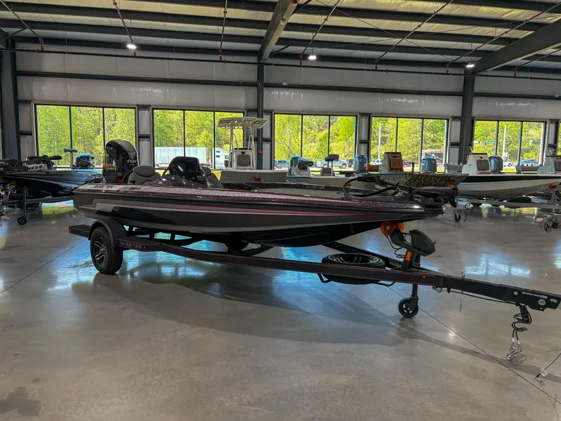 Slide: The Image of 2025 Skeeter ZX150 boat in showroom, on trailer, with large windows in background. - 1