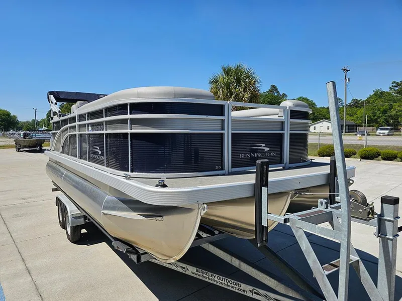 Slide: The Image of 2021 Bennington 20 SSR pontoon boat on trailer, parked outdoors under clear blue sky. - 5