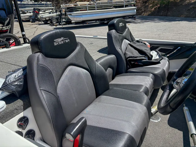 Slide: The Image of 2014 Skeeter FX 21 boat interior with black and gray seats, parked near other boats. - 10