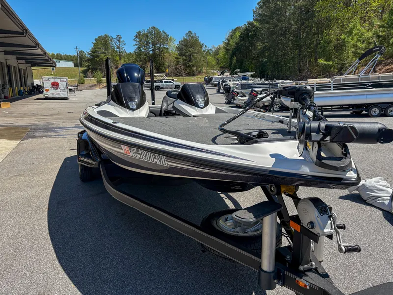 Slide: The Image of 2014 Skeeter FX 21 boat parked outdoors, surrounded by trees and other boats. - 6