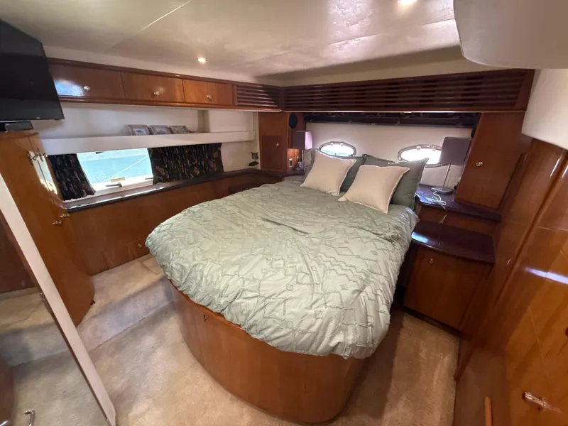 Slide: The Image of Luxurious 2001 Carver 396 Motor Yacht bedroom with cozy bed and elegant wood finishes. - 23