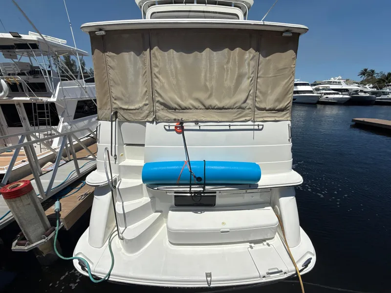 Slide: The Image of 2001 Carver 396 Motor Yacht docked, rear view with blue fender and covered deck. - 3