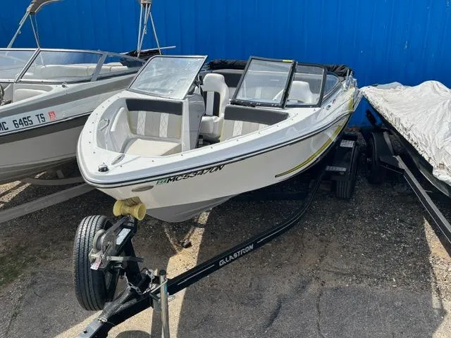 Slide: The Image of 2021 Glastron GTS 185 boat on trailer, parked outdoors near a blue wall. - 13