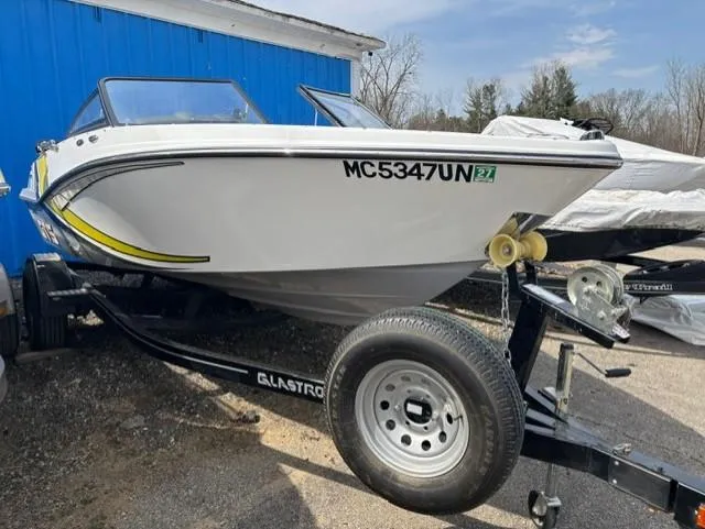 Slide: The Image of 2021 Glastron GTS 185 boat on trailer, parked outdoors near a blue building. - 14