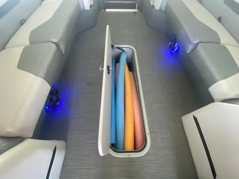 Slide: The Image of 2018 Crest Caliber 250 SLRC boat interior with open storage compartment and colorful pool noodles. - 28