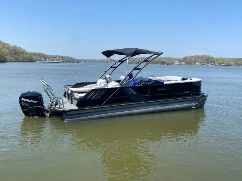 Slide: The Image of 2018 Crest Caliber 250 SLRC pontoon boat on a calm lake with a Mercury outboard motor. - 36