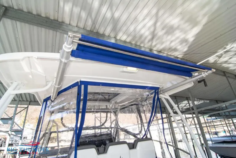 Slide: The Image of 2020 Jeanneau Leader 10.5 boat with blue canopy and clear enclosure under a metal roof. - 20