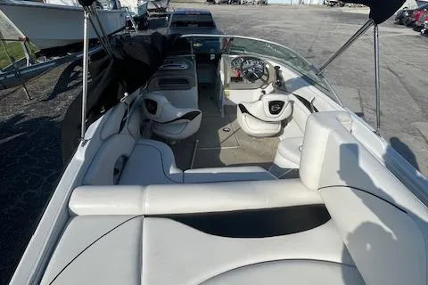 Slide: The Image of 2008 Crownline 230 LS boat interior with seating and steering wheel, docked outdoors. - 16