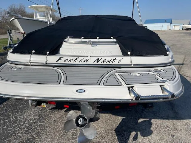 Slide: The Image of 2008 Crownline 230 LS boat with "Feelin' Nauti" text on the stern, covered and docked. - 18