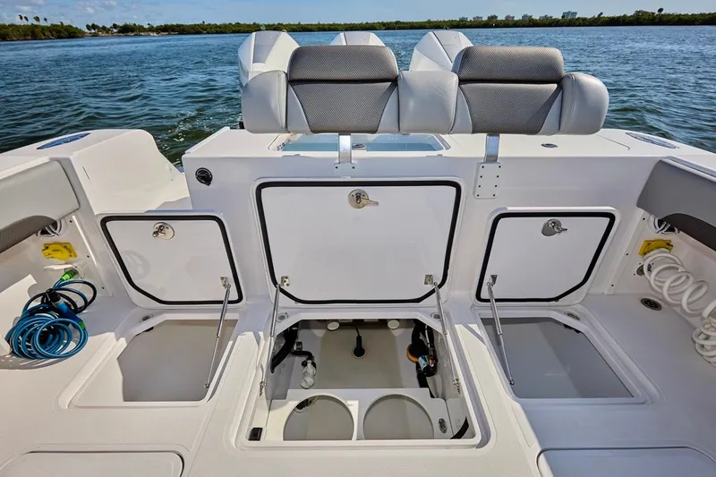 Slide: The Image of 2022 Bluewater 35 boat with open storage compartments on deck, docked on calm water. - 2