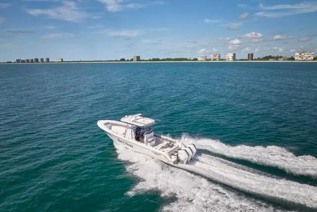 Slide: The Image of 2022 Bluewater 35 boat cruising on open water with coastal buildings in the background. - 74