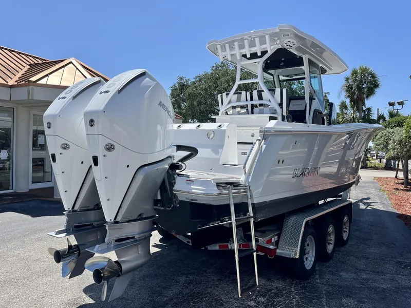 Slide: The Image of 2023 Blackfin 272 boat with dual Mercury engines on a trailer, parked outdoors. - 6