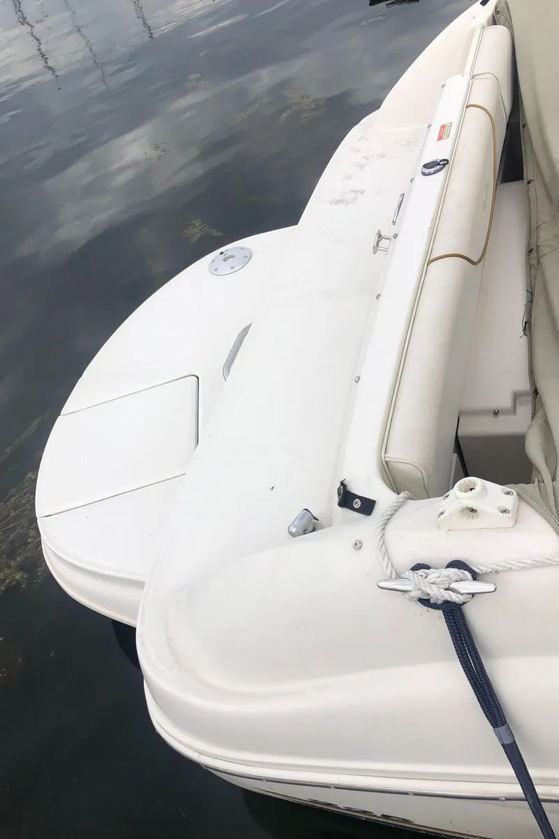 Slide: The Image of 2001 Sea Ray 225 Weekender boat, white seating and deck, docked on calm water. - 16