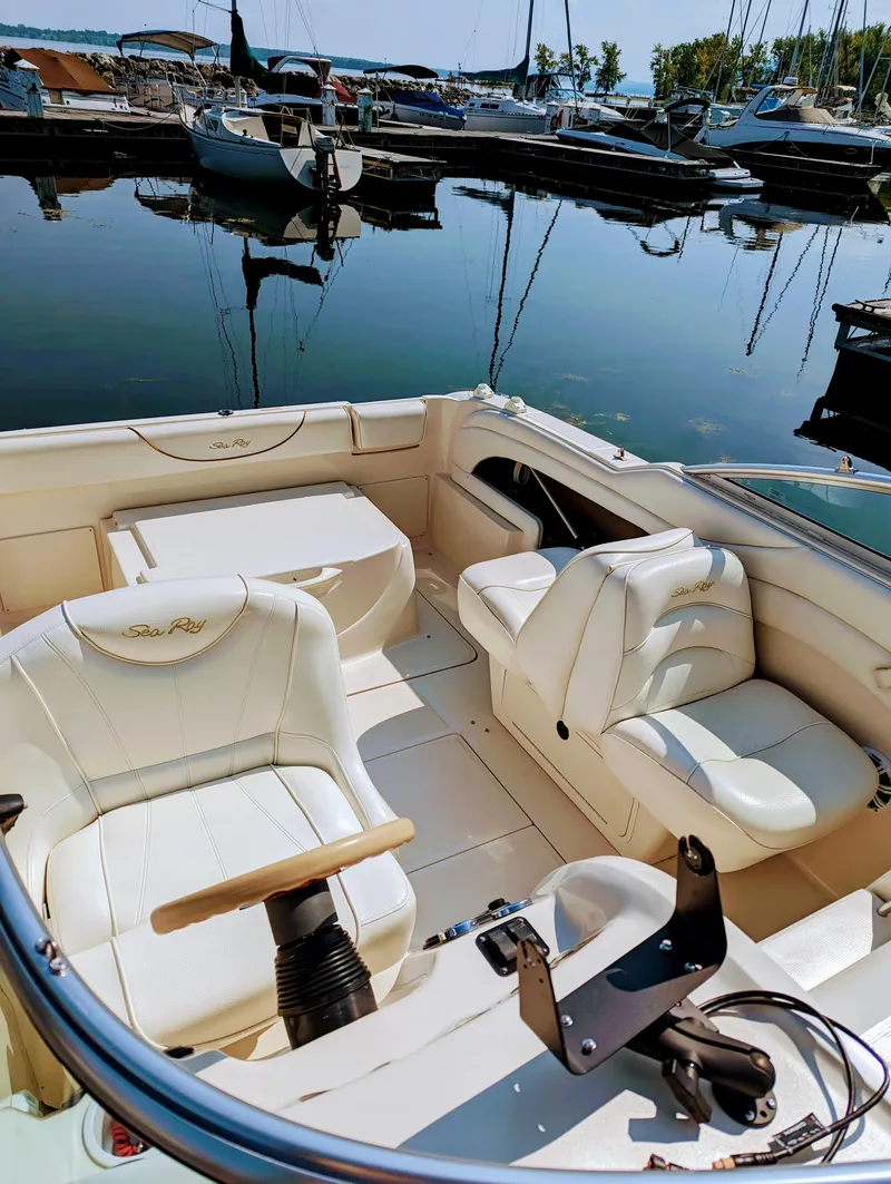 Slide: The Image of 2001 Sea Ray 225 Weekender boat interior with white seating, docked at a marina. - 7