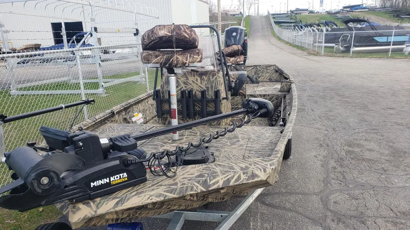Slide: The Image of 2021 Lowe RTX1760PT camo fishing boat with Minn Kota motor, parked near a fence. - 5