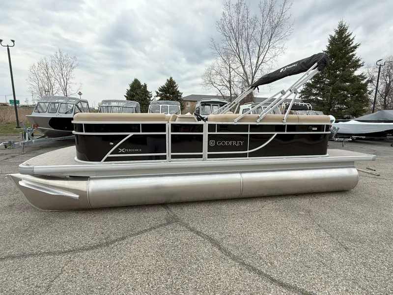 Slide: The Image of 2025 Godfrey EX2086CX pontoon boat parked on pavement, featuring sleek design and modern amenities. - 2