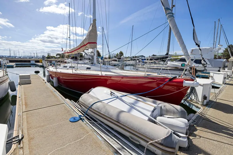 Slide: The Image of Red 1994 J Boats J/130 sailboat docked with inflatable dinghy, under clear blue sky. - 3